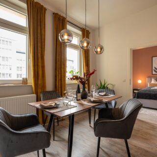 Airbnb-Esszimmer einrichten lassen: Großer Esstisch mit Stühlen und warmen Lichtakzenten für gesellige Abende