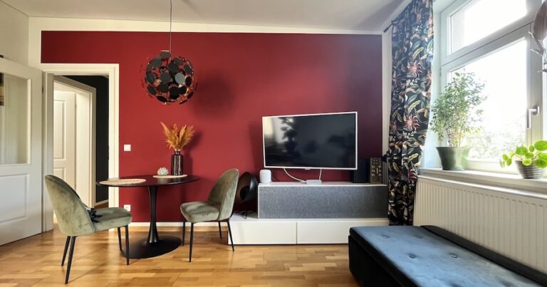 Modernes Wohnzimmer mit warmer Wand in kräftigem Rot und kleiner Essecke