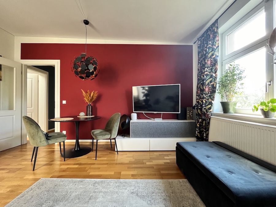 Modernes, kleines Wohnzimmer mit warmer Wand in kräftigem Rot und kleiner Essecke