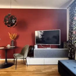 Modernes Wohnzimmer mit warmer Wand in kräftigem Rot und kleiner Essecke
