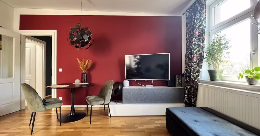 Modernes Wohnzimmer mit warmer Wand in kräftigem Rot und kleiner Essecke